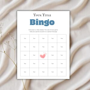 May include: A white Bingo game card with a grid of boxes, a pink heart graphic, and the word "Bingo" in blue. The card includes space for a title and instructions. The background is a light beige fabric.