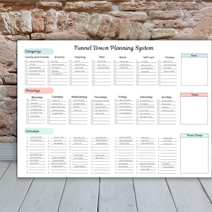 May include: A white planner titled "Funnel Down Planning System" with sections for categorization, prioritization, and scheduling. The planner includes checkboxes for tasks related to family, grocery, cleaning, pets, work, self-care, and fitness.