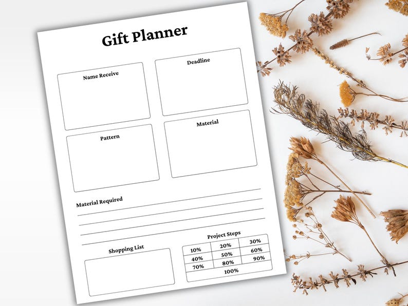 May include: A white Gift Planner sheet with sections for Name, Deadline, Pattern, and Material. It includes a shopping list and project steps with percentage breakdowns. Dried flowers are arranged on the white surface.