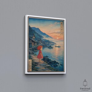 May include: A framed canvas print featuring a coastal scene with a small figure in a red dress standing on a stone path by the water. The artwork depicts a sunset over the ocean, mountains, and traditional houses, with Japanese text on the sides.