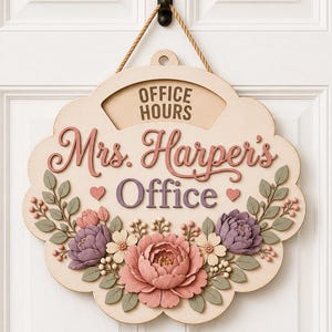 以下が含まれることがあります： ロープで吊るされたスカラップ型の木製看板。「OFFICE HOURS」、「Mrs. Harper's」、「Office」という文字が刻まれています。看板は、ピンク、紫、クリーム色の立体的な花の装飾と緑の葉で飾られています。