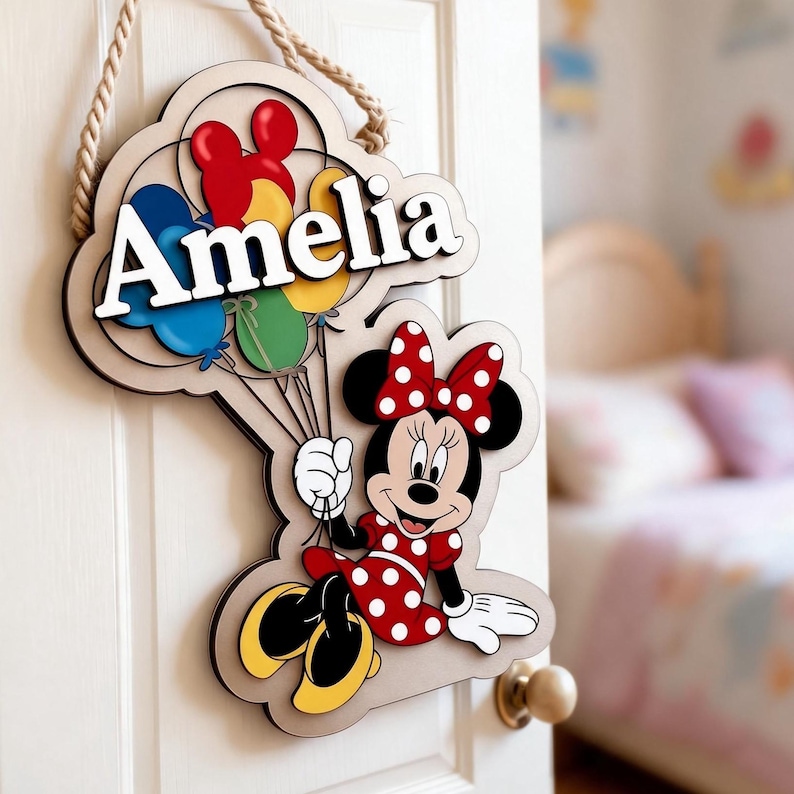 May include: Wooden door sign with Minnie Mouse holding balloons. The sign says "Amelia" in white letters. Minnie Mouse is in a red dress with white polka dots and a matching bow. The balloons are red, blue, green, and yellow.