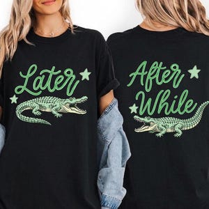 Pode incluir: Camiseta preta com um gráfico de jacaré verde e o texto "Later" na frente. A parte de trás da camisa apresenta o texto "After While" e um design de jacaré correspondente. A camisa é um estilo casual unissex.