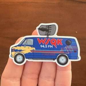 May include: A sticker featuring a blue van with the text "WSQK 94.5 FM" in red and a yellow eagle design. The van has a radio antenna on top and colorful stripes along the side.