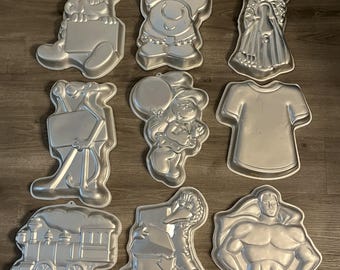 Moldes para pasteles con personajes vintage: Pitufos, Ziggy, Holly Hobby, Pantera Rosa, Pitufina, Molde para pastel con forma de camiseta y tren, Big Bird y Superman.