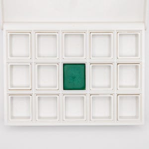 Può includere: Una tavolozza per acquerelli bianca con 16 pozzetti quadrati, uno riempito con una vivace vernice verde. La tavolozza ha un coperchio incernierato e i pozzetti sono disposti a griglia. Ideale per artisti e hobbisti.