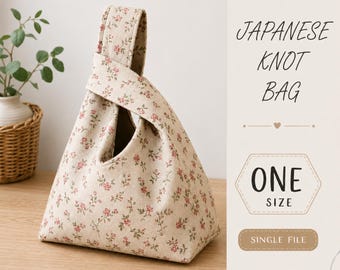 May include: A Japanese knot bag made of beige fabric with a small red and green floral pattern. The bag features a unique handle design where one strap is longer than the other to loop through. Text on the right reads JAPANESE KNOT BAG ONE SIZE.