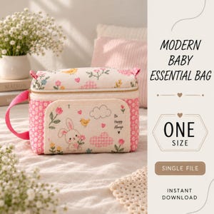 Puede incluir: Un bolso rectangular para artículos de bebé en tela color crema con un patrón de flores rosas, pequeños pájaros amarillos y una ilustración central de un conejo blanco sosteniendo una flor. El bolso tiene paneles laterales rosas y el texto Be Happy Always.