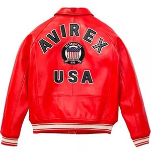 May include: A red leather jacket with the text "AVIREX" arched across the back in white block letters. Below the text is a circular patch with the words "ALL AMERICANS" and a US flag design. The word "USA" is printed in white block letters below the patch.
