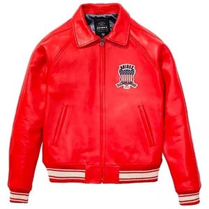 May include: A vibrant red leather jacket with a classic collar and a zip-up front. The jacket features a white and red striped ribbed hem and cuffs. An embroidered patch with the text "AVIREX" and a patriotic design is on the chest.