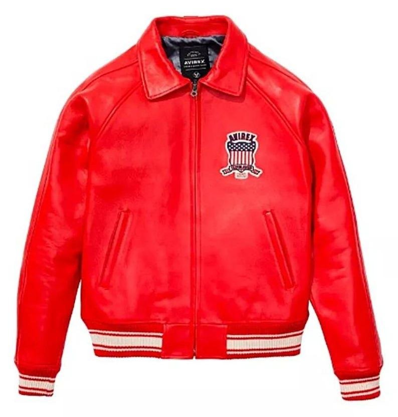 May include: A vibrant red leather jacket with a classic collar and a zip-up front. The jacket features a white and red striped ribbed hem and cuffs. An embroidered patch with the text "AVIREX" and a patriotic design is on the chest.
