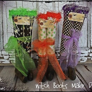 Könnte beinhalten: Drei dekorative Hexenstiefel mit verschiedenen Mustern und Farben. Ein Stiefel ist schwarz mit weißen Skeletten, ein anderer ist weiß mit grünen Punkten, und der letzte ist braun mit weißen Punkten. Jeder Stiefel hat eine andersfarbige Tüllschleife und -verzierung. Der Text "witch boots make do" ist sichtbar.