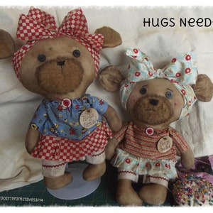 May include: Two handmade plush teddy bears with red and white checkered bows and floral print bows. The bears are wearing colorful outfits and have a tag that says "Hugs Needed".