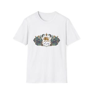 Puede incluir: Camiseta blanca con un emblema detallado. El emblema presenta un león dorado, una corona y patrones ornamentados en verde azulado, azul y dorado. Se incluye texto en una fuente de escritura. Una prenda informal para el día a día.