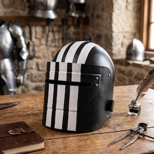 May include: A black and white striped medieval helmet sits on a wooden table. The helmet has a visor and is decorated with vertical white stripes. Other medieval armor is visible in the background.