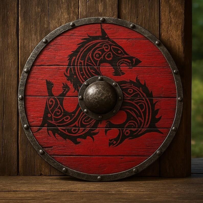 May include: A circular wooden shield painted in red with a black stylized wolf design. The shield features a dark metal rim secured with rivets and a central metal boss. The wood grain is visible beneath the red paint, creating a textured surface.