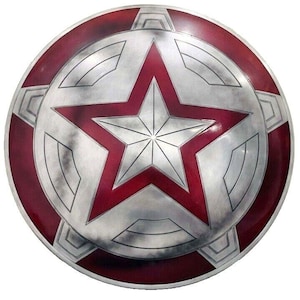 May include: A round, metallic shield with a red and silver star design. The shield has a red border and a silver center with a large red star in the middle. The star is surrounded by a silver geometric pattern.