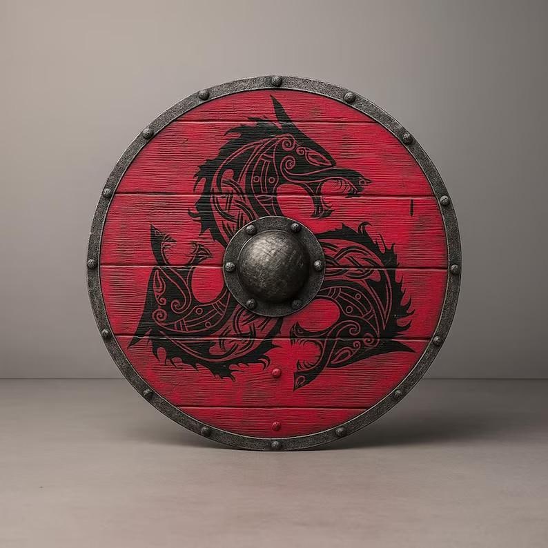 May include: A circular wooden shield featuring a vibrant red finish with a prominent black dragon motif. The shield is bordered by a dark metallic rim with evenly spaced rivets and includes a central domed metal boss for added structural detail.