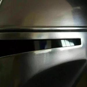 May include: Close-up of a metallic silver helmet with a visor. The helmet has a smooth, reflective surface with visible details and contours. The visor is dark, and the overall design suggests a futuristic or sci-fi theme.