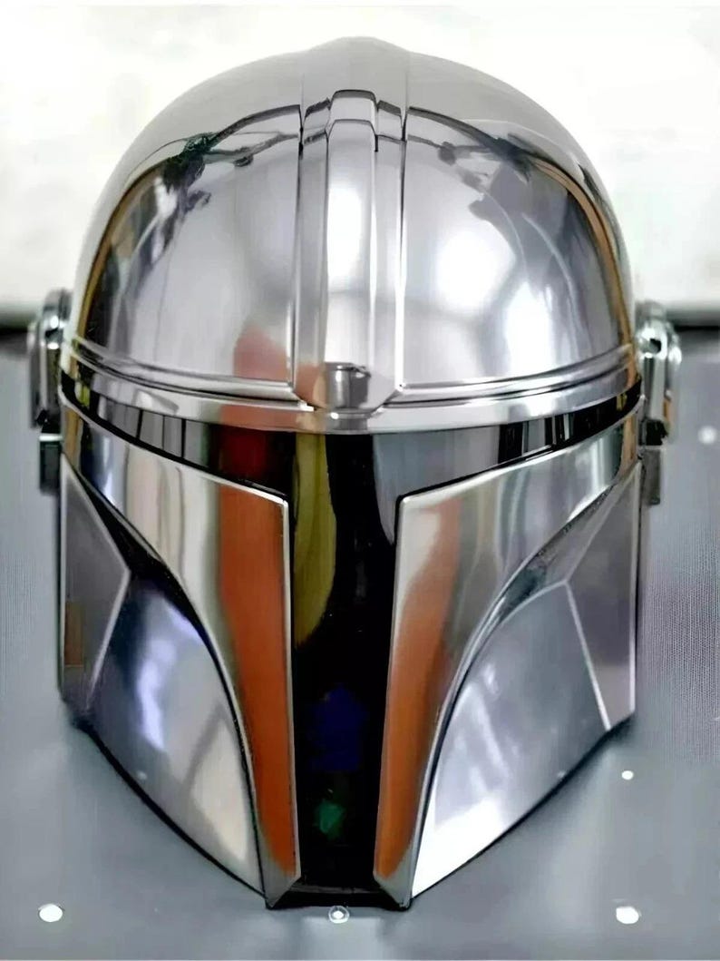 May include: A highly reflective, silver-colored helmet with a distinctive design. The helmet features a rounded top, a visor, and angular cheek plates. The surface is smooth and polished, reflecting the surrounding environment. The overall aesthetic suggests a futuristic or science fiction theme.