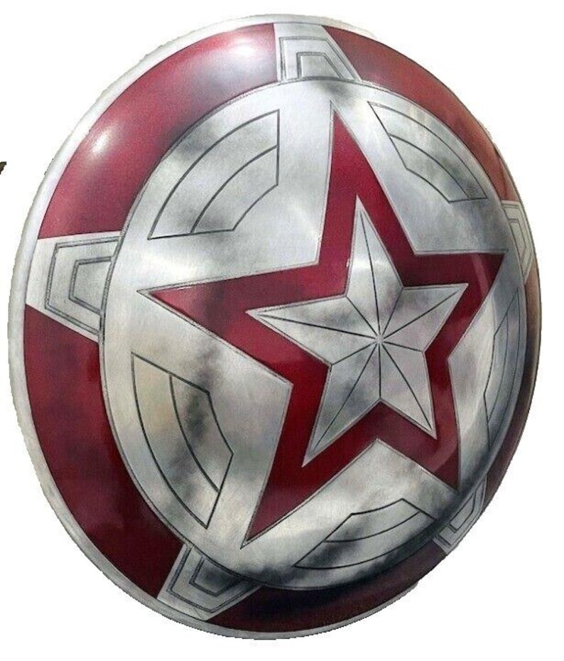 May include: A round, metallic shield with a red and silver color scheme. The shield features a large red star in the center, surrounded by a silver star and a red outer ring. The design is reminiscent of a superhero's shield.