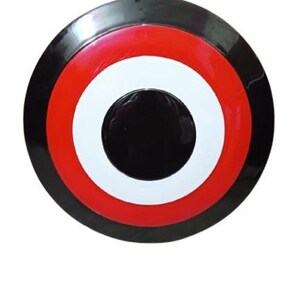May include: A round shield with a black outer ring, followed by a red ring, a white ring, and a black center. The shield has a glossy finish and is set against a white background.