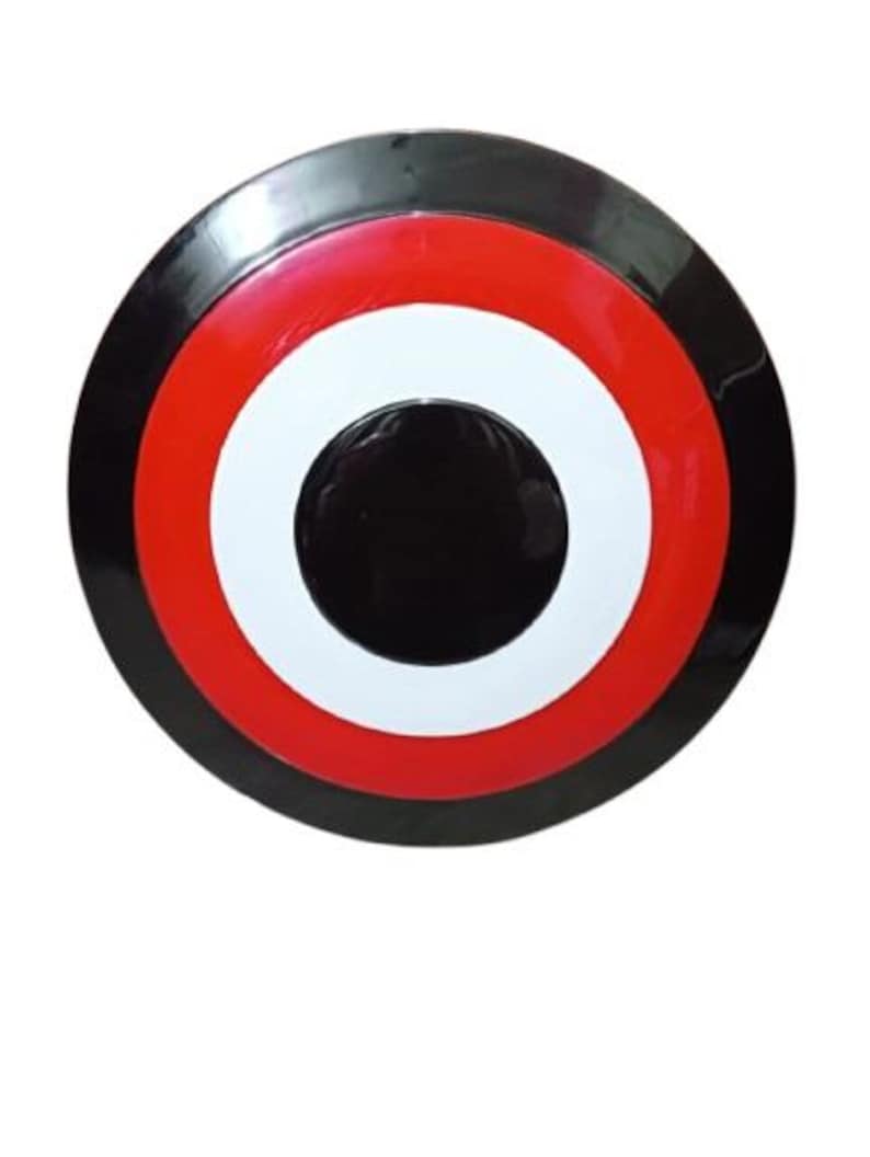 May include: A round shield with a black outer ring, followed by a red ring, a white ring, and a black center. The shield has a glossy finish and is set against a white background.