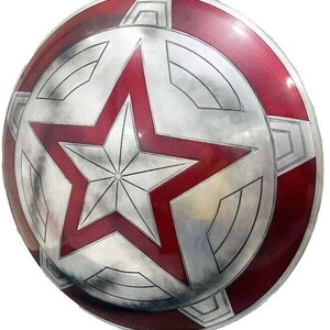 May include: A round, metallic shield with a red and silver color scheme. The shield features a large, red star in the center, surrounded by a silver design. The outer rim is also red, with silver accents. The shield has a weathered appearance.