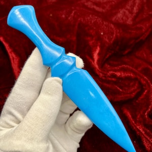 May include: A bright blue, smooth, solid-coloured dagger-shaped object with a tapered, pointed blade and a contoured handle. The item features a uniform, matte-like finish across its entire surface, showcasing a sleek, symmetrical design.