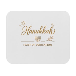 May include: A white square coaster with rounded corners. The coaster features the word "Hanukkah" in gold script, along with a Star of David, a menorah, and the phrase "Feast of Dedication" in a serif font.
