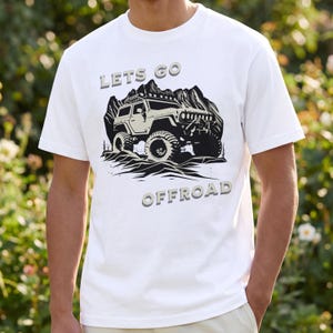 Puede incluir: Camiseta blanca con un gráfico de un vehículo todoterreno y una cordillera. El texto "LETS GO OFFROAD" está impreso encima y debajo del vehículo en una fuente gris en 3D. La camiseta es de manga corta.