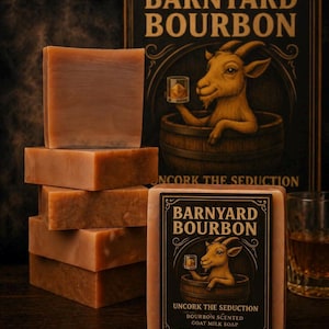 以下が含まれることがあります： 「Barnyard Bourbon」と「Uncork the Seduction」の文字が入った、茶色の長方形のヤギミルク石鹸が積み重ねられています。ラベルには、樽の中で飲み物を持っているヤギが描かれています。琥珀色の液体が入ったグラスが見えます。