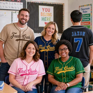 May include: A collection of five button-down baseball jerseys in various colors including tan, navy blue, pink, green, and black. The jerseys feature text such as Fourth Grade, First Grade, and Jaxon 7, with pinstriped patterns on the pink and green shirts.