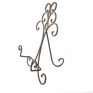 May include: A decorative, wrought iron display stand with a dark brown finish. The stand features a scrolled design with multiple curved elements and a base for holding items. The stand is designed to hold plates or other decorative items.