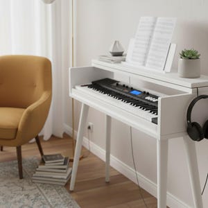Può includere: Un pianoforte digitale bianco con tastiera nera e leggio con spartiti. Il pianoforte ha un ripiano integrato con una piccola pianta succulenta e un paio di cuffie nere. Sullo sfondo, una poltrona gialla.