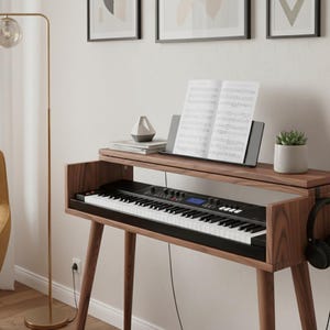 May include: A wooden piano stand with a black keyboard and white keys. Sheet music rests on a stand above the keyboard. A small succulent in a grey pot and a geometric sculpture are also on the stand. Headphones hang on the side.