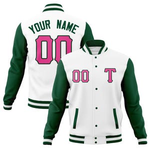 May include: White varsity jacket with green sleeves and trim. The jacket features the text "YOUR NAME" and the number "00" in pink on the back. The front displays the number "00" and the letter "T" in pink.