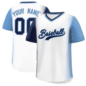 May include: White baseball jersey with light blue sleeves and trim. The front features the word "Baseball" in navy blue script. The back displays the text "YOUR NAME" above the number "00" in navy blue.