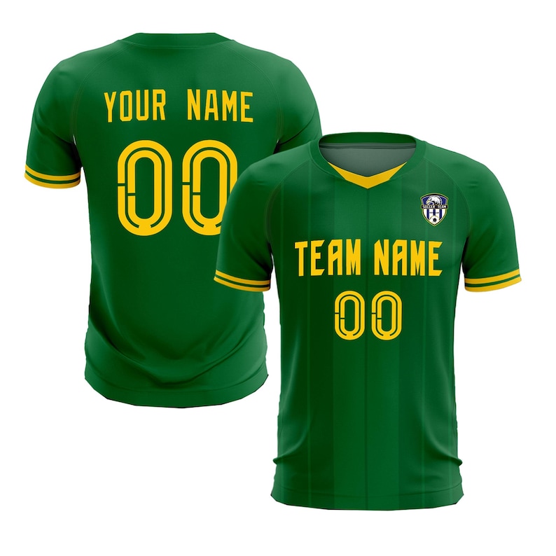 May include: Green soccer jersey with yellow accents. The front displays "TEAM NAME" and the number "00" in yellow. The back of the jersey shows "YOUR NAME" and the number "00". A team logo is on the upper chest.