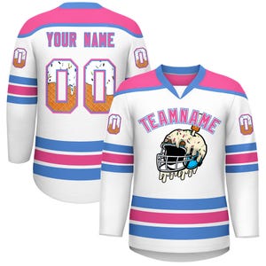 Pode incluir: Camisola de hóquei branca com detalhes rosa e azul. A camisola apresenta "YOUR NAME" e "00" nas costas e "TEAMNAME" na frente. Apresenta um gráfico de capacete de sorvete.