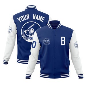 May include: A blue and white varsity jacket with the text "YOUR NAME" and a baseball player graphic on the back. The front of the jacket has a large white "B" and a "CUSTOM LOGO" circle. The sleeves are white with blue stripes.