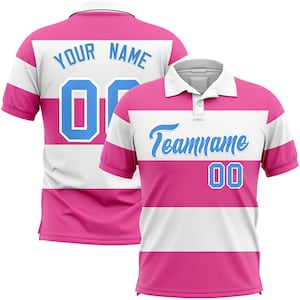 May include: A pink and white polo shirt with short sleeves. The shirt has a white collar and a three-button placket. The front of the shirt has the text "Teamname" in light blue script, with the number "00" below. The back of the shirt has the text "YOUR NAME" and the number "00".