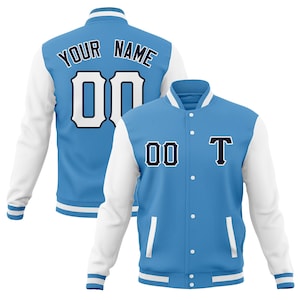 May include: Two light blue and white letterman jackets. The jackets have white sleeves and a light blue body. One jacket has the text "YOUR NAME" above the number "00". The other jacket has the number "00" and the letter "T".