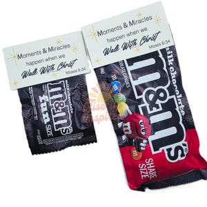Peut inclure: Deux paquets de bonbons au chocolat M&M's, un format amusant et un format à partager, avec des cartes attachées. Les cartes indiquent "Moments & Miracles happen when we Walk With Christ" et "Moses 6:34". L'emballage des bonbons est noir et rouge.