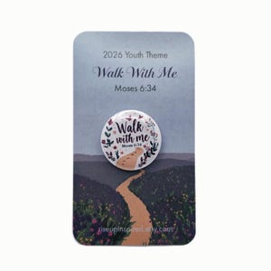 May include: A pin with the text "Walk With Me" and "Moses 6:34" on a card with a landscape design. The pin is white with floral accents and a path illustration. The card has the text "2026 Youth Theme".