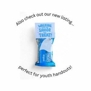 Pu&ograve; includere: Una barretta Rice Krispies Treats nella sua confezione blu originale, sormontata da un cartoncino bianco con il testo blu "WALKING WITH THE SAVIOR IS A TREAT!" circondato da piccole icone a forma di stella rosa e gialle su sfondo bianco.