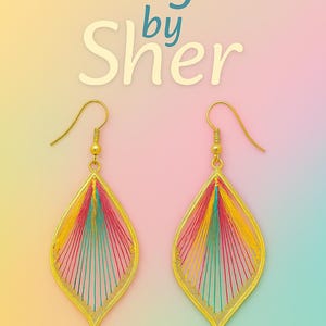 May include: A pair of gold-colored, teardrop-shaped earrings. The earrings are filled with colorful threads in red, yellow, and teal. The text "Designs by Sher" is displayed in the image.