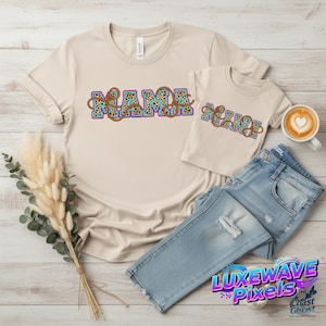 May include: Two beige t-shirts, one adult and one child size, with the words "MAMA" and "MINI" in a colorful leopard print design. Light blue jeans and a cup of coffee with a heart-shaped design are also in the image.