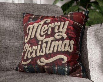 May include: A square decorative pillow with a red and green plaid pattern. The pillow features the words "Merry Christmas" in a cream-colored, textured font. The pillow is resting on a gray sofa.