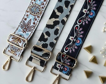May include: Three adjustable bag straps with gold-tone metal hardware. The left strap features a light blue floral pattern, the center strap has a grey and black leopard print, and the right strap displays a black background with floral motifs.